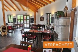 Gastraum des Restaurants im Schwarzwald-Sportzentrum Neubulach mit Holzdecke, Kachelofen und Bestuhlung – Objekt verpachtet